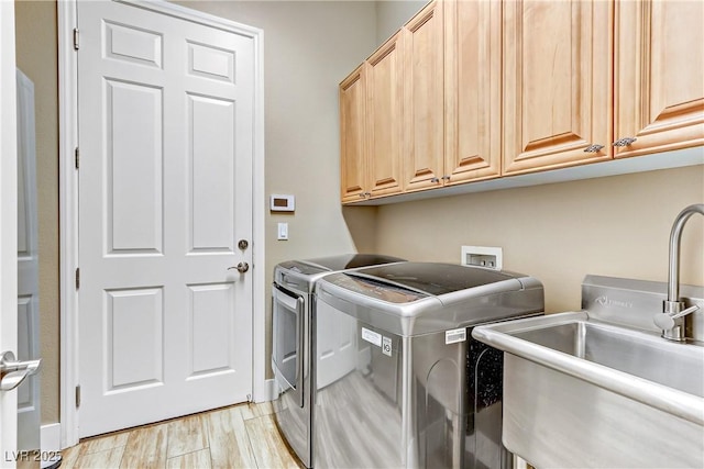 washroom with cabinets, sink, washer and clothes dryer, and light wood-type flooring