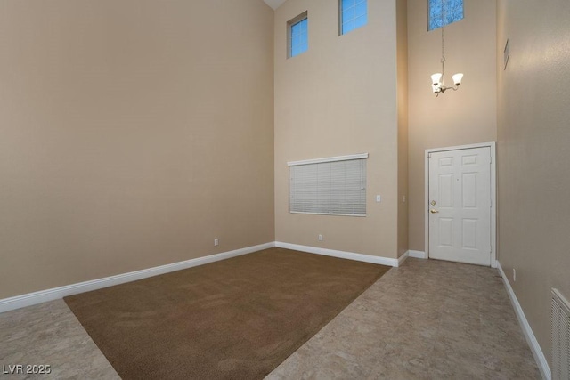 entrance foyer with an inviting chandelier, a towering ceiling, and dark colored carpet