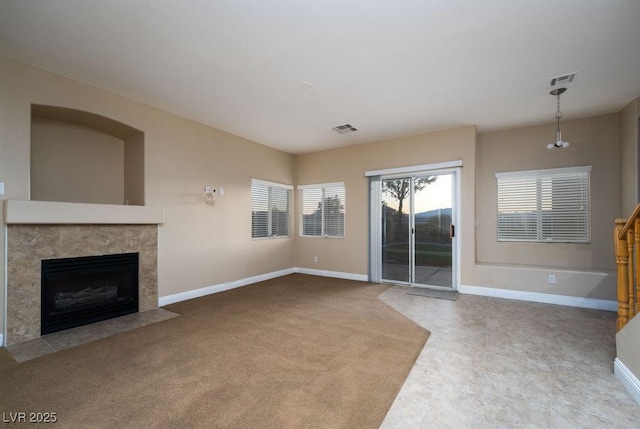 unfurnished living room with a tiled fireplace and carpet flooring