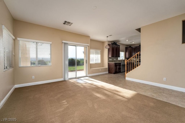 unfurnished living room featuring plenty of natural light and light carpet