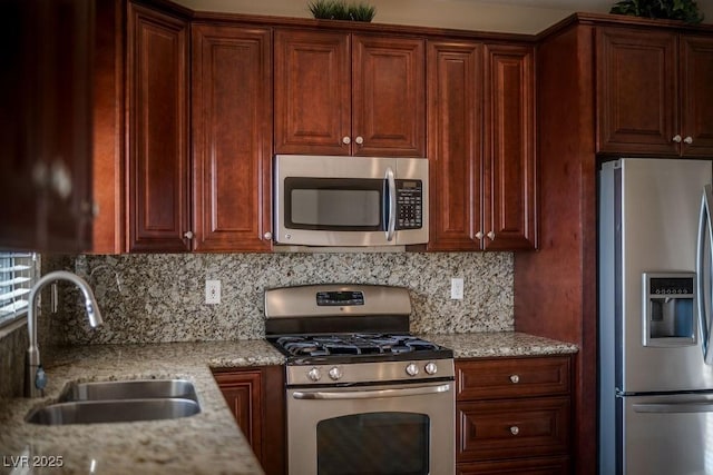 kitchen with tasteful backsplash, appliances with stainless steel finishes, light stone countertops, and sink