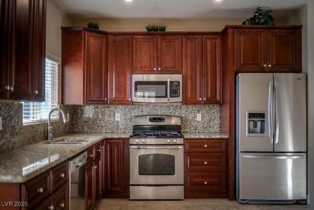 kitchen with light stone counters, appliances with stainless steel finishes, sink, and decorative backsplash