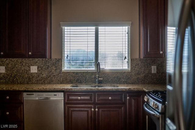 kitchen with sink, dark stone countertops, dark brown cabinets, stainless steel appliances, and decorative backsplash