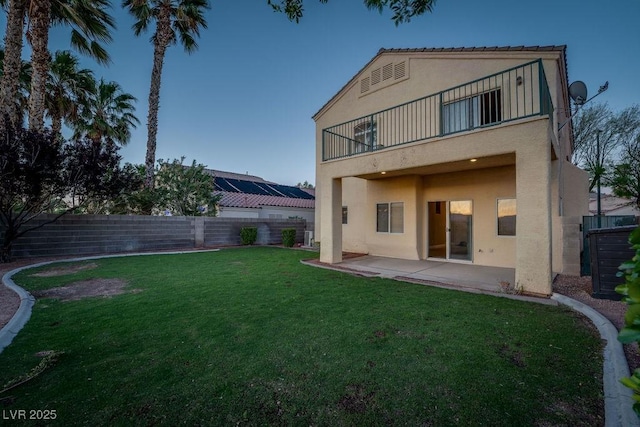 rear view of property featuring a balcony, a patio, and a lawn