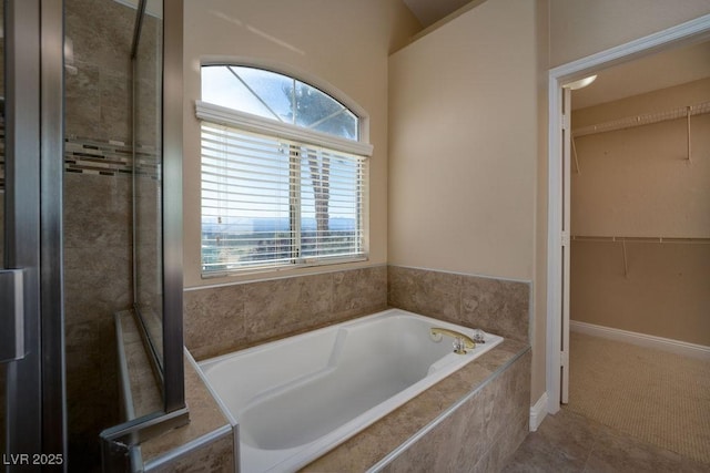 bathroom with a relaxing tiled tub and tile patterned flooring