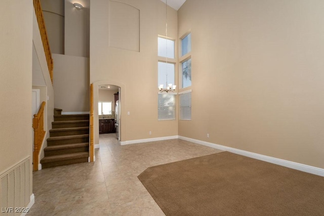 interior space with a notable chandelier, light tile patterned floors, and a high ceiling