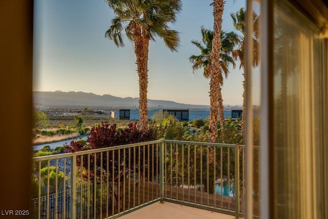 balcony at dusk featuring a water and mountain view