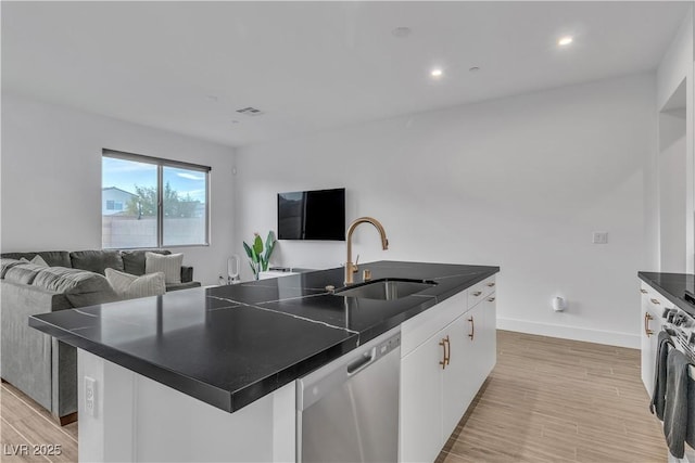 kitchen featuring sink, white cabinets, a kitchen island with sink, stainless steel dishwasher, and light hardwood / wood-style flooring