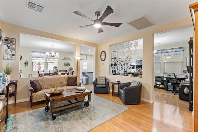 living room featuring ceiling fan with notable chandelier and light hardwood / wood-style flooring