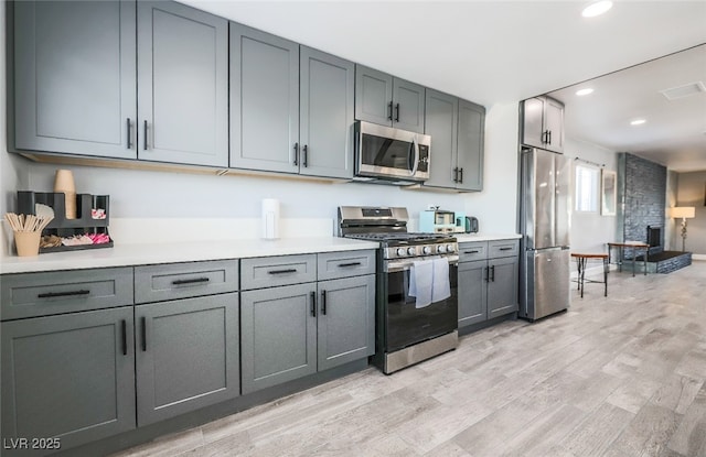 kitchen featuring appliances with stainless steel finishes, light hardwood / wood-style floors, and gray cabinetry