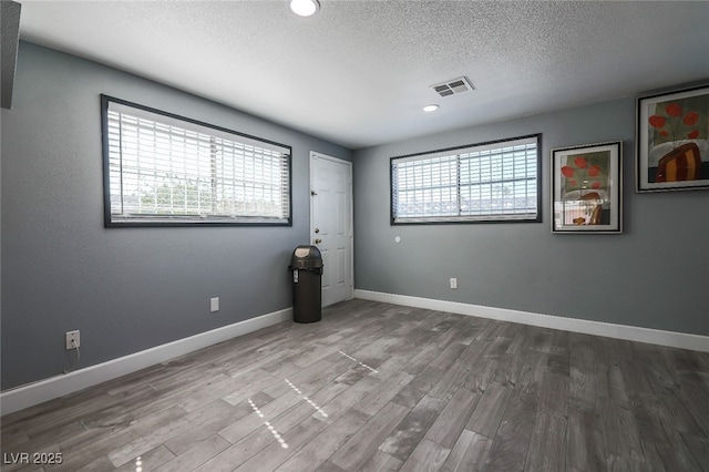 unfurnished room with hardwood / wood-style floors, a textured ceiling, and a healthy amount of sunlight