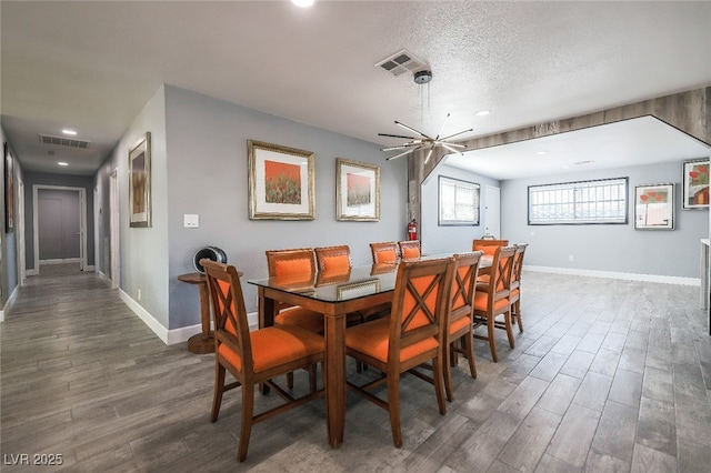 dining space featuring dark hardwood / wood-style floors, a textured ceiling, and a notable chandelier