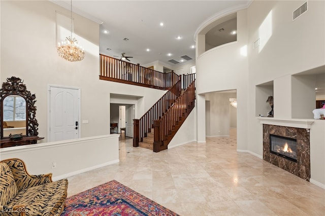 living room with ornamental molding, a tiled fireplace, and ceiling fan with notable chandelier