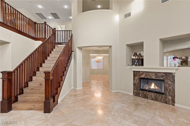 stairway with crown molding, a healthy amount of sunlight, a fireplace, and a towering ceiling