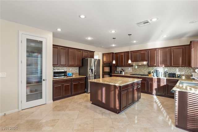 kitchen featuring a kitchen island, sink, hanging light fixtures, light stone counters, and stainless steel appliances