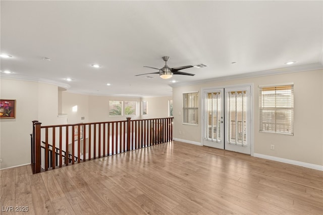 empty room featuring french doors, ornamental molding, ceiling fan, and light hardwood / wood-style flooring