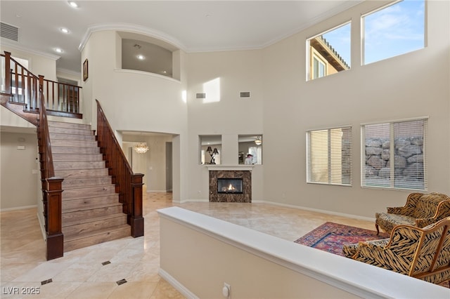 tiled living room featuring crown molding, an inviting chandelier, and a tile fireplace