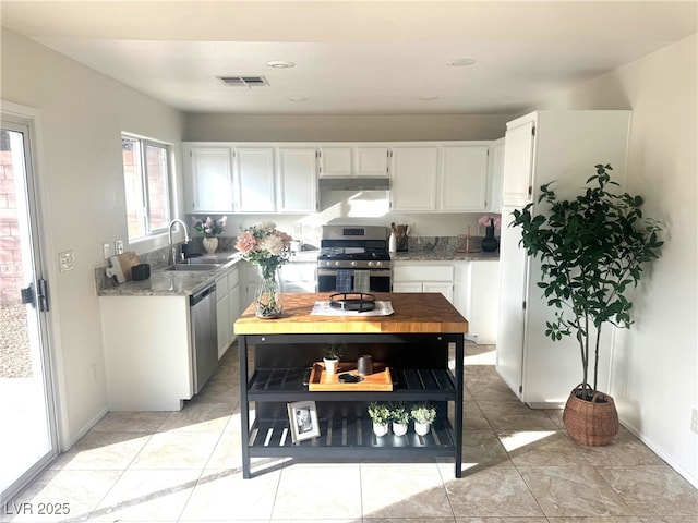 kitchen featuring appliances with stainless steel finishes, light stone countertops, sink, and white cabinets