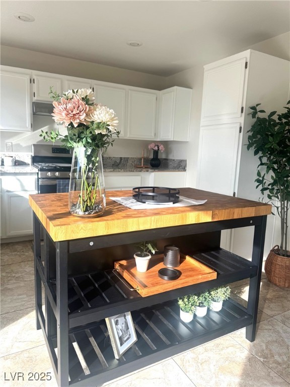 kitchen with wood counters, white cabinetry, and gas range