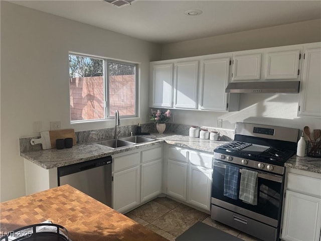 kitchen featuring stainless steel appliances, white cabinetry, sink, and light stone counters