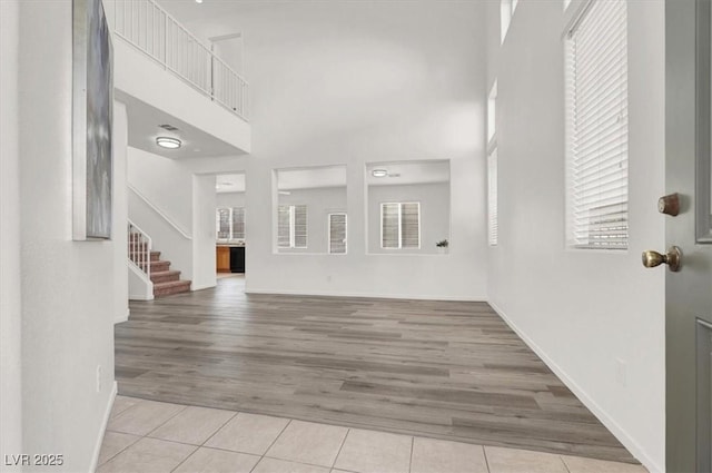 unfurnished living room with light tile patterned flooring and a towering ceiling