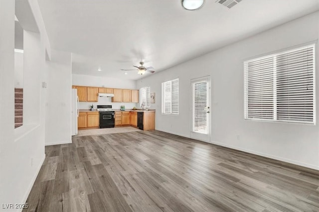 kitchen with light brown cabinetry, range with gas stovetop, light hardwood / wood-style floors, and dishwasher