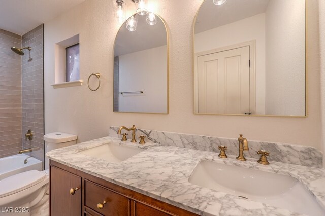 bathroom featuring toilet, double vanity, a sink, and bathing tub / shower combination