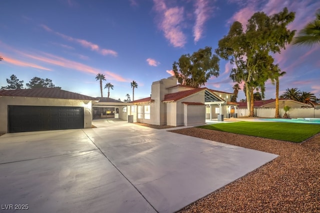 view of front of house with an attached garage, fence, concrete driveway, and stucco siding