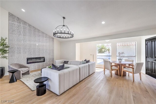 living room with light wood-style floors, lofted ceiling, a fireplace, and recessed lighting