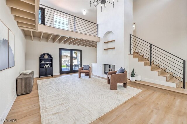 foyer entrance featuring wood finished floors, baseboards, french doors, stairway, and a glass covered fireplace