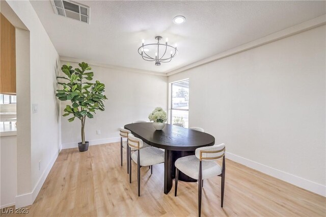 dining area featuring visible vents, an inviting chandelier, light wood-style floors, a textured ceiling, and baseboards