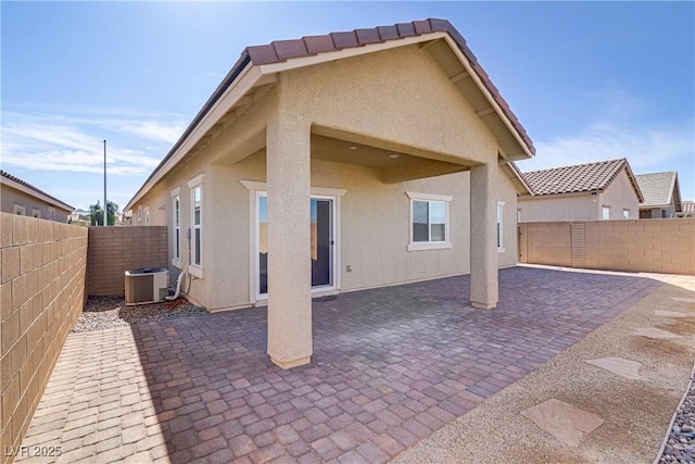 back of property with central AC unit and a patio area