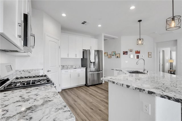 kitchen with white cabinets, sink, stainless steel fridge, and decorative light fixtures