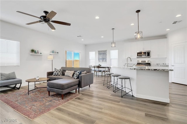 living room with ceiling fan and light wood-type flooring