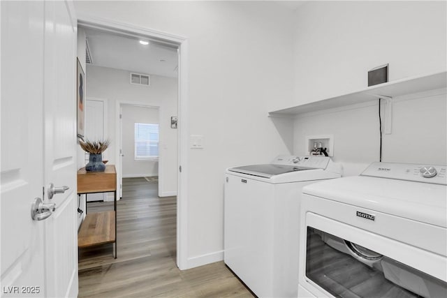 clothes washing area with independent washer and dryer and light hardwood / wood-style floors