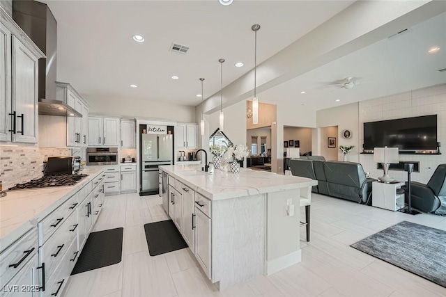 kitchen featuring pendant lighting, a large island, wall chimney range hood, and white cabinets