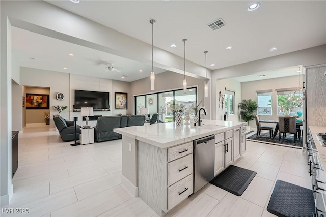 kitchen with appliances with stainless steel finishes, sink, hanging light fixtures, a kitchen island with sink, and light tile patterned floors