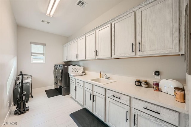 clothes washing area with cabinets, sink, and washer and dryer