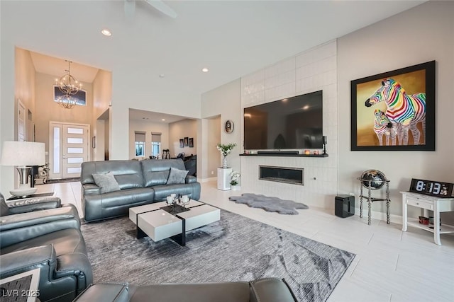 living room with a tiled fireplace, tile patterned floors, and an inviting chandelier