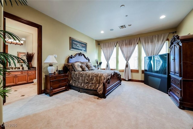 bedroom featuring light colored carpet and ensuite bath