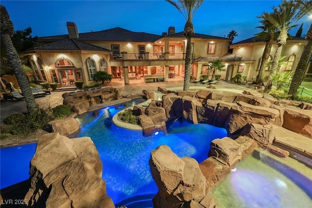 pool at dusk with french doors, a patio, and an in ground hot tub