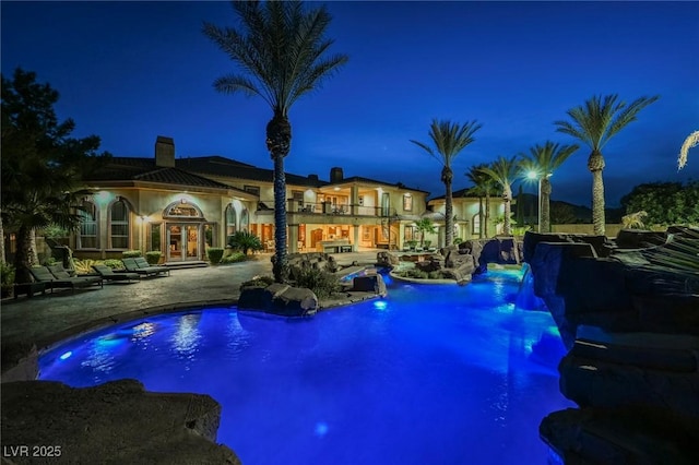 pool at twilight with a patio area and french doors