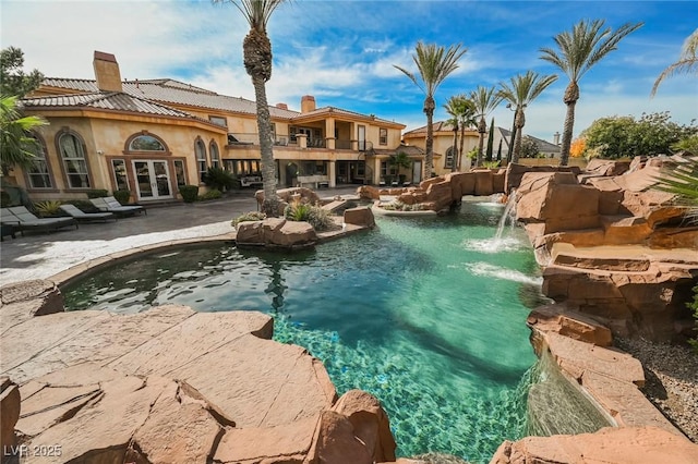 view of pool with a patio, french doors, and pool water feature