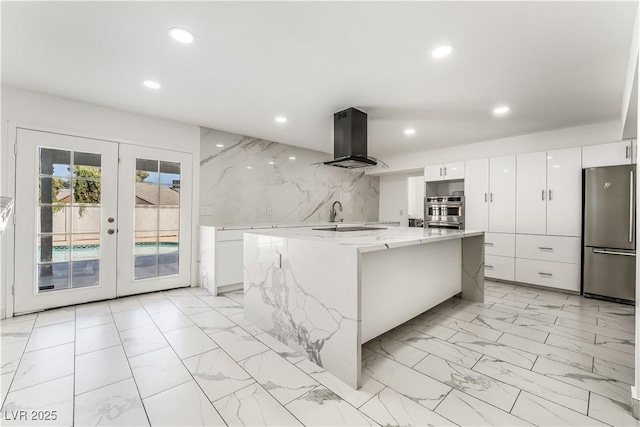 kitchen featuring ventilation hood, a spacious island, stainless steel fridge, white cabinets, and french doors