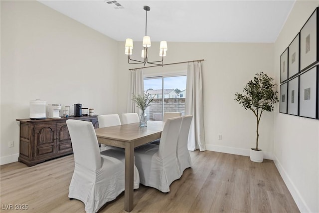 dining room featuring an inviting chandelier, lofted ceiling, and light hardwood / wood-style floors