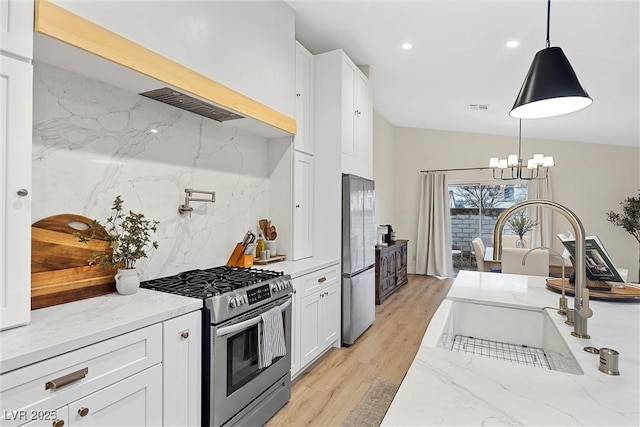 kitchen featuring appliances with stainless steel finishes, light stone countertops, sink, and hanging light fixtures