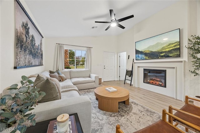 living room with wood-type flooring, ceiling fan, and vaulted ceiling