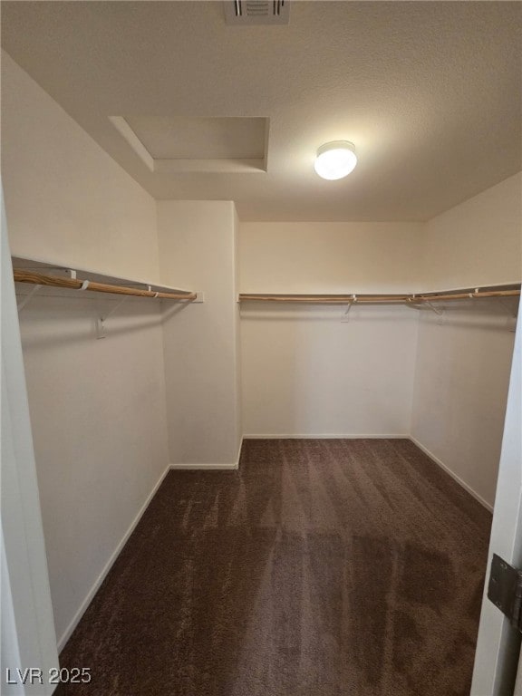 spacious closet featuring attic access, visible vents, and dark carpet