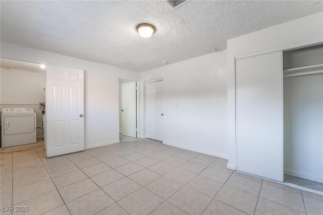 unfurnished bedroom featuring washer and dryer, light tile patterned floors, a textured ceiling, and a closet