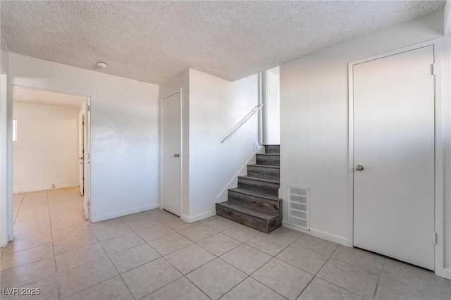 stairway featuring tile patterned flooring and a textured ceiling